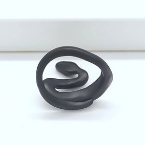 Close-up of minimalist black matte snake-shaped open ring with sleek S-curve design