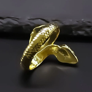 Detailed view of golden snake ring with realistic scale texture on dark stone background
