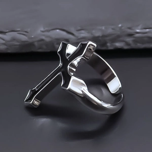 Detail of a punk cross open ring on dark stone texture with gothic minimalist design