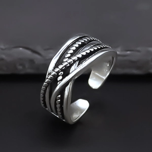 Macro detail of punk style irregular weave alloy ring on a dark stone texture background