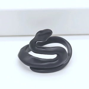 Macro shot of minimalist matte black snake-shaped adjustable ring with creative design
