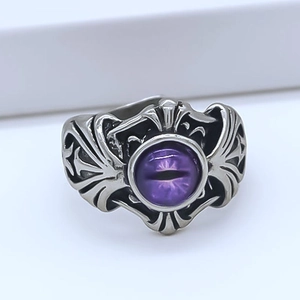 Macro detail of gothic ring featuring a purple devil eye and vintage wing relief