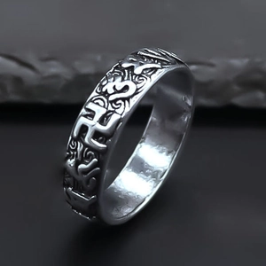 Macro detail of retro distressed wide band ring featuring embossed Buddhist religious symbols