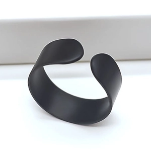 Detail view of a minimalist wide matte black open ring with sleek curved metal surface