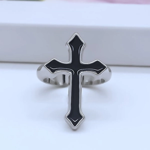 Close-up of punk style silver cross ring with black enamel inlay and vintage patterns