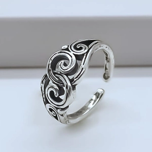 Close-up of vintage silver open ring featuring engraved scroll patterns and oxidized details