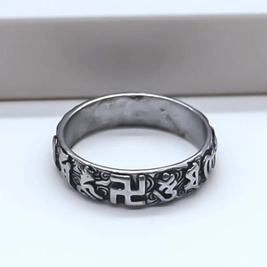 Detail of vintage silver alloy ring featuring embossed religious symbols and distressed finish