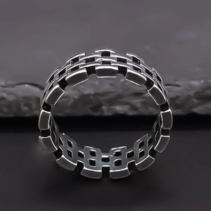 Macro detail of silver industrial chain woven ring on a dark textured rock background