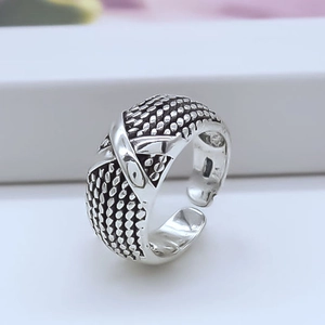 Macro detail of silver-plated adjustable open ring featuring a braided texture and X-cross design
