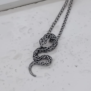Macro view of silver snake pendant with detailed scales on a square box chain