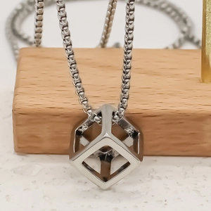 Collana minimalista con ciondolo a cubo d'argento e catena box su espositore in legno uomo