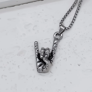 Detailed macro view of retro rock hand gesture pendant on fine square pearl chain