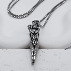 Gros plan d'un pendentif figurine féminine en argent avec bikini sur surface en pierre