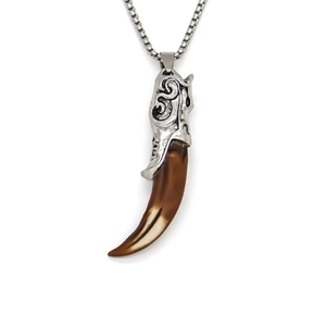 Macro view of vintage tribal wolf tooth pendant with ornate floral metal engraving