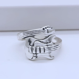 Detailed close-up of adjustable silver guitar shaped ring with engraved music strings