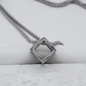 Vista macro del ciondolo a cubo geometrico argento con catena lucida per coppie