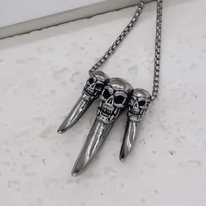 Macro shot of punk skeleton claw pendant with box chain on stone surface