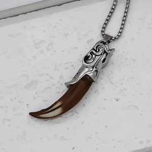 Macro detail of men's wolf tooth pendant with vintage relief and stainless steel chain