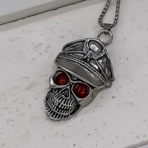 Macro shot of a gothic punk skull pendant with red gemstone eyes and an eagle cap
