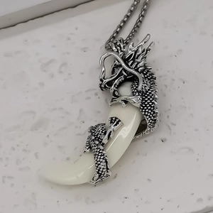 Vue détaillée d'un dragon argenté sculpté s'enroulant sur un pendentif en forme de croc