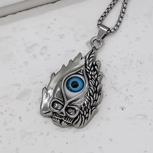 Detail of vintage silver skull pendant with blue evil eye and textured flame carvings