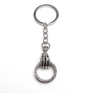 Macro view of retro silver skull hand pendant holding a twisted ring on a keychain