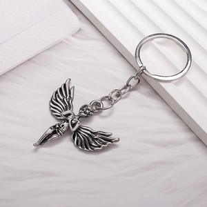 Vintage silver angel pendant keychain with detailed wings on a white textured background