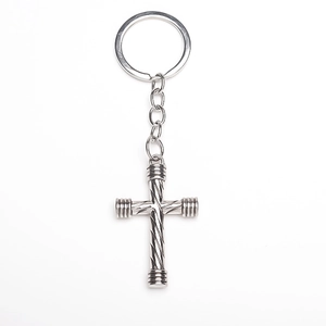 Macro detail of a silver metallic cross keychain with spiral texture and polished finish