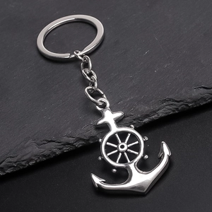 Silver anchor and helm nautical keychain on dark stone background with metal ring