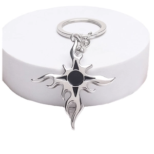 Silver vintage flame cross keychain with black centerpiece on a white podium