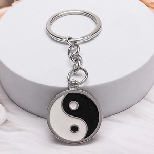 Minimalistischer Yin-Yang-Glas-Schlüsselanhänger aus Silbermetall auf weißem Präsentationsständer