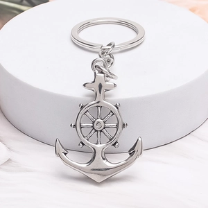 Minimalist silver alloy anchor and helm keychain with circular metal ring on white feather