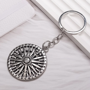 Vintage silver compass keychain with numeric dial and metallic chain on white plush background