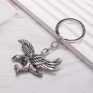 Antique silver eagle keychain with detailed feathers in diving pose on plush background