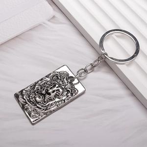 Retro silver metal lion head keychain with embossed pendant on white faux fur background