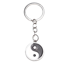 Silberner Schlüsselanhänger mit rundem Yin-Yang-Glasanhänger auf reinweißem Hintergrund