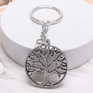 Vintage Tree of Life keychain with silver hollow pendant on white plush background