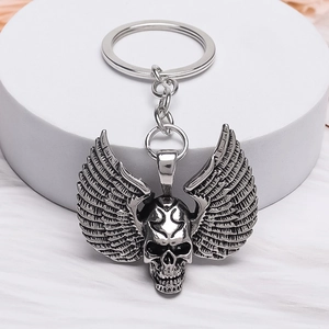 Retro punk gothic skeleton skull with detailed feather wings metal keychain on white pedestal