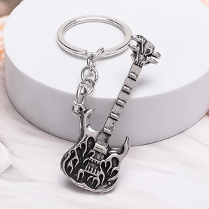 Guitar keychain in vintage silver finish with flame relief pattern on a white pedestal