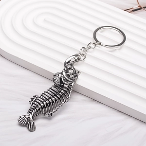 Vintage silver fish bone keychain accessory with intricate alloy skeletal design on a stand