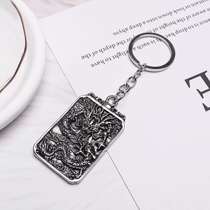 Close-up of vintage silver square keychain with detailed dragon relief and metal ring