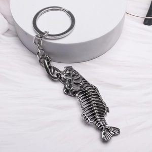Detailed close-up of dark silver alloy fishbone keychain on a white textured background