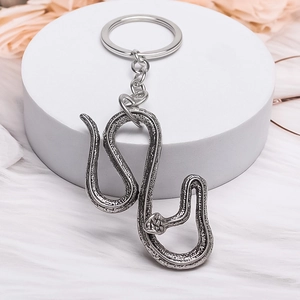 Silver vintage snake keychain with detailed scale texture on white stone stand