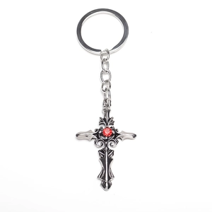 Detail of gothic silver alloy cross keychain with vintage textures and red rhinestone