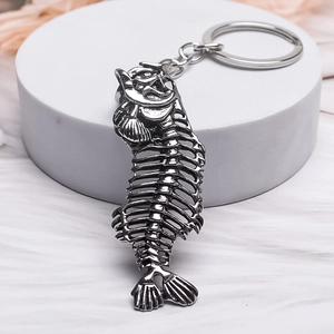 Unique fish skeleton metal keychain with vintage silver finish on a white display stand
