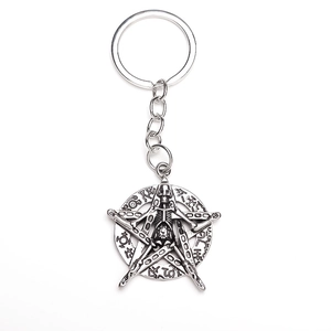 Close-up of antique silver skull and pentagram keychain with intricate occult runes