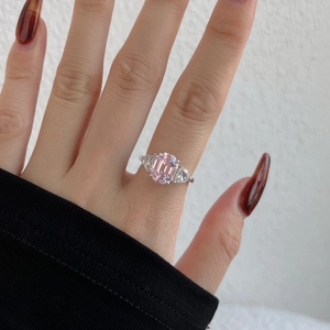Detail view of pink emerald-cut gemstone ring with triangular side stones on hand