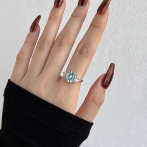 Detail of S925 silver ring featuring emerald cut blue zircon on female finger