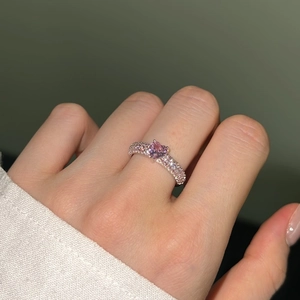 Close-up of heart-shaped pink zircon ring with pavé-set gemstones on a silver band