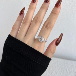 Macro detail of emerald cut zircon silver ring with pear cut side stones on finger